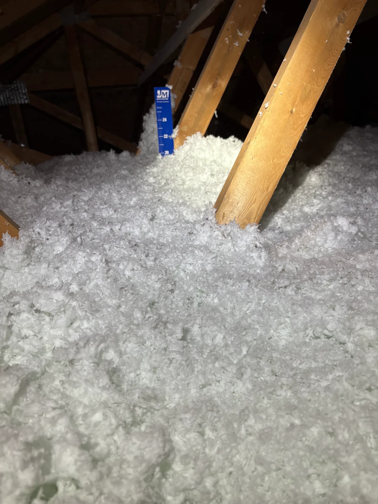 An insulation depth gauge confirming coverage in a finished attic