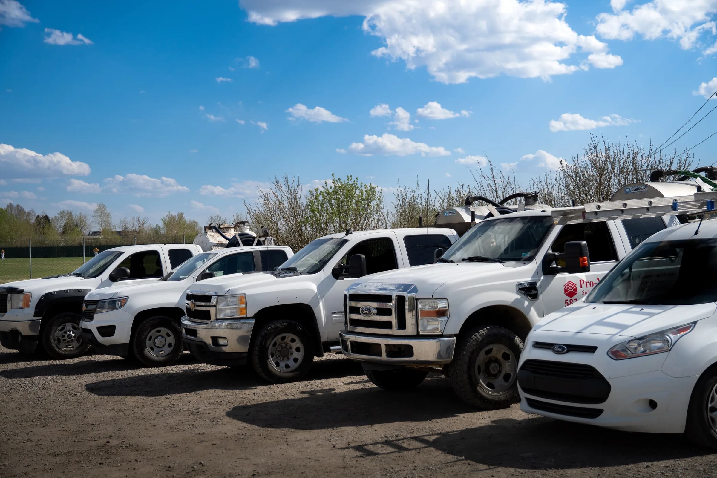 The Pro-Pest Solutions fleet of pickups and a service van with tanks and ladder racks