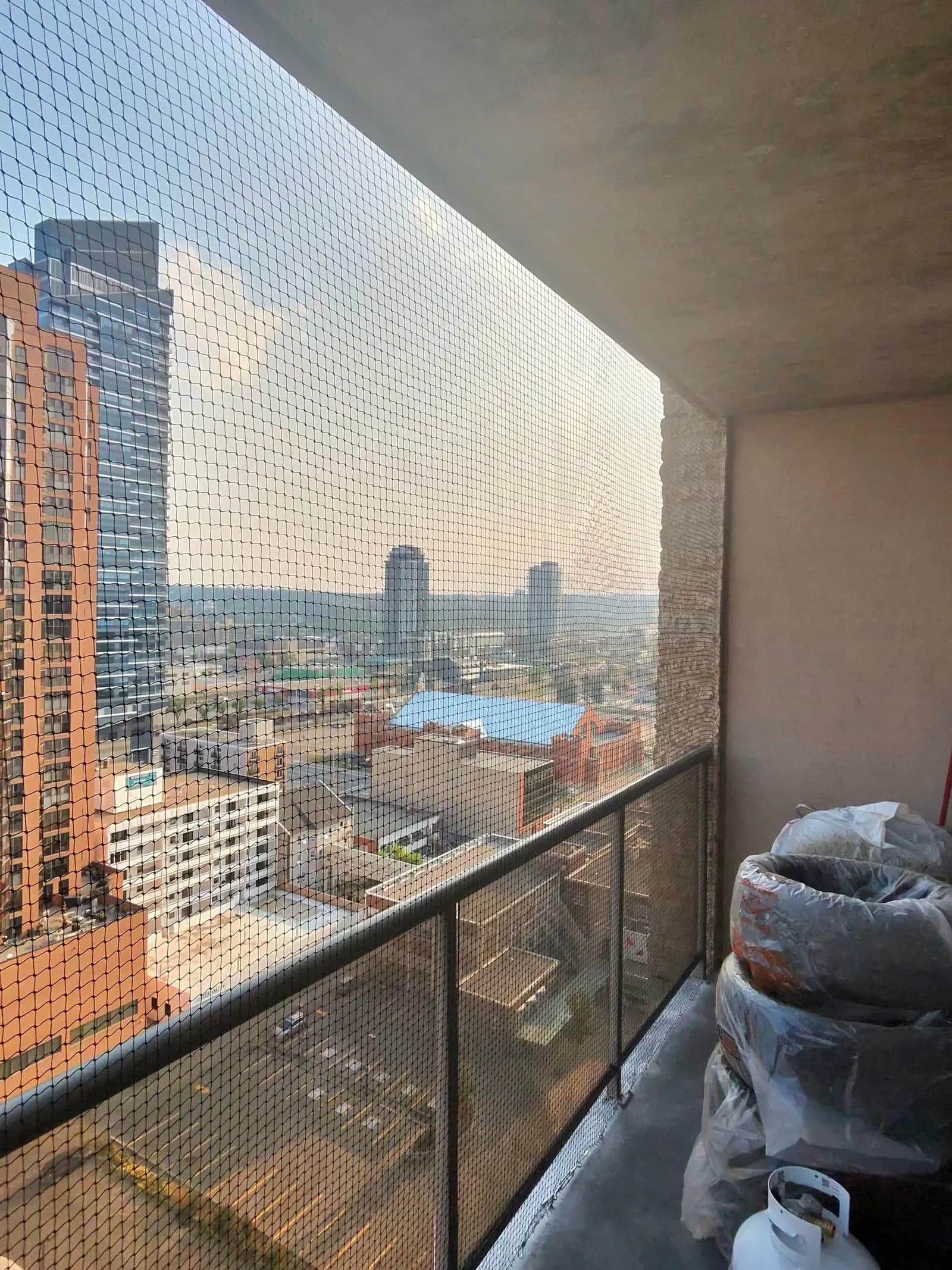 A high-rise balcony enclosed with bird netting at dusk