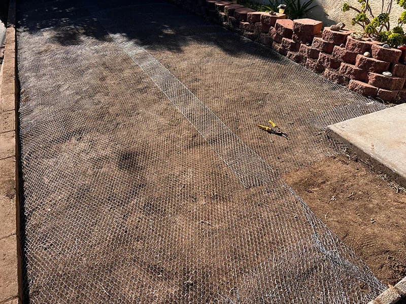 Wire mesh staked across a yard to stop burrowing rodents