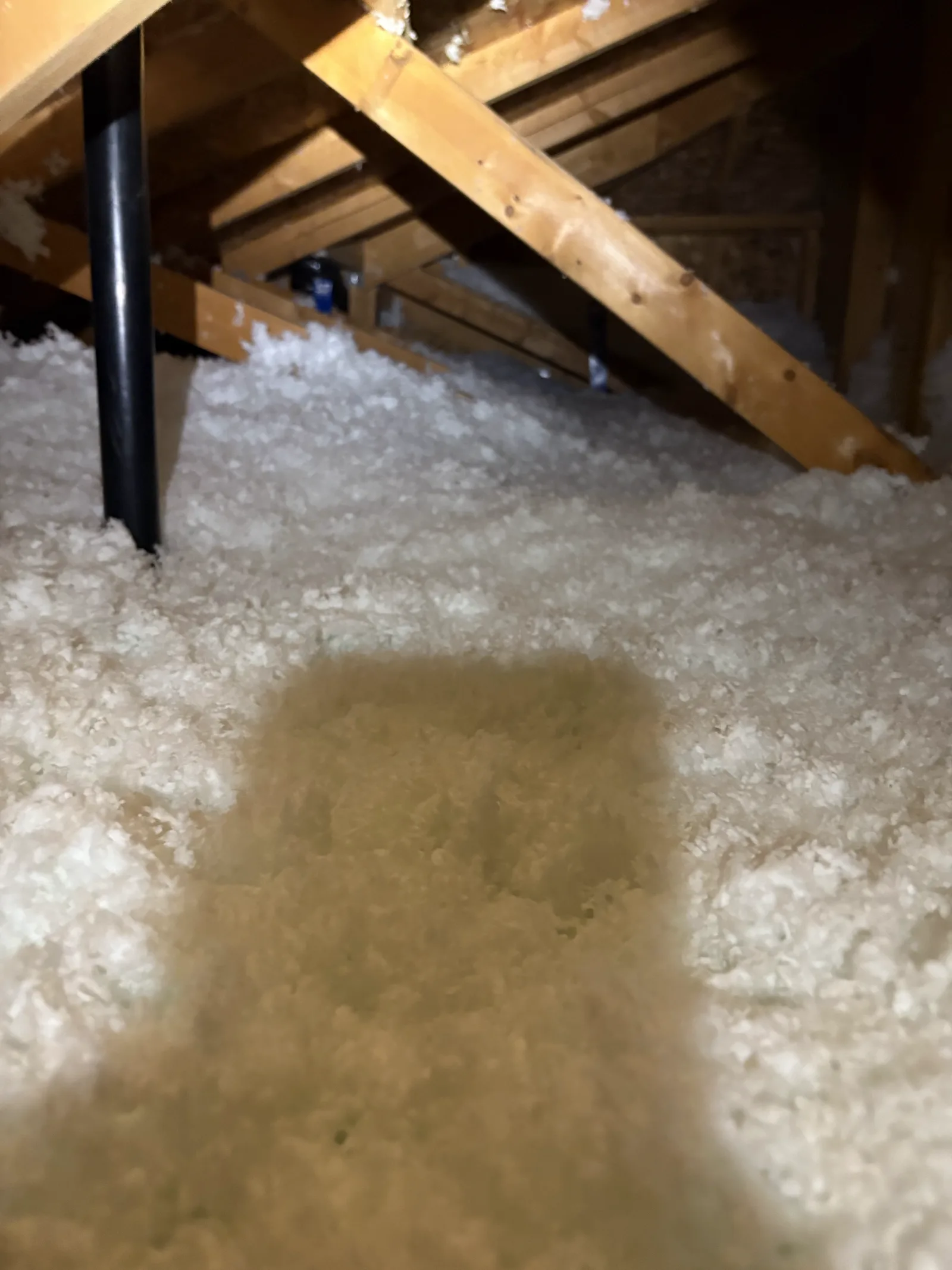 A finished attic with fresh blown-in insulation around the flue